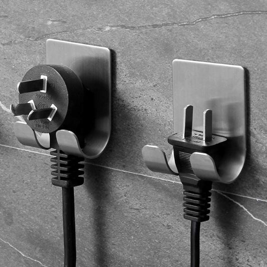 This image displays two sleek, stainless steel double hooks, each supporting a power plug against a gray stone wall. The hooks are self-adhesive, boasting a modern design that combines functionality with minimalist style, holding the plugs securely without the need for additional tools.