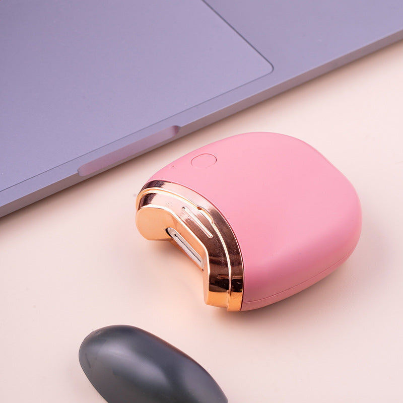 Featured in a soft pink hue, this Electric Fingernail Clipper showcases its portable size beside a sleek, grey laptop. The device's sleek curvature and rose gold trim highlight its stylish and user-friendly appeal.