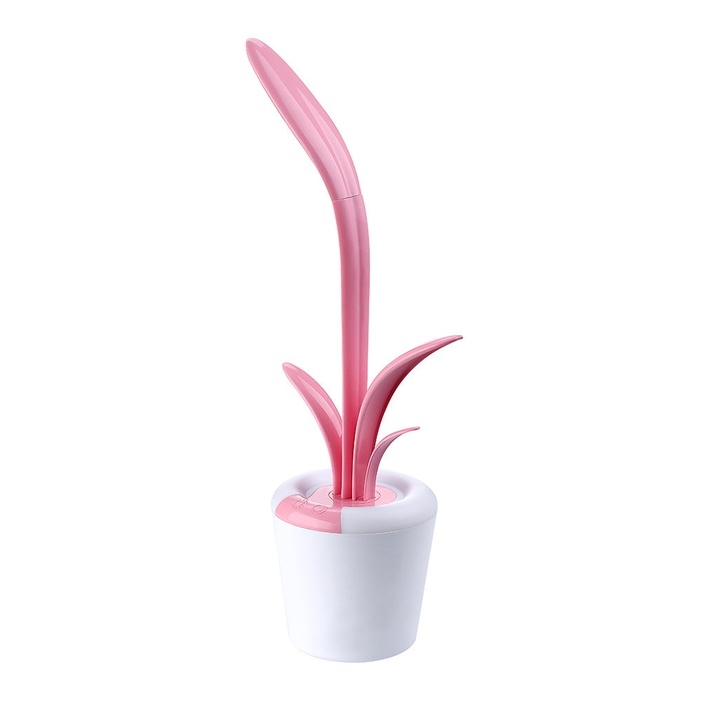 mage displays a single pink Clivia LED Table Lamp. The lamp, resembling a stylized plant, has a white, pot-like base and two green, leaf-shaped elements that extend upward. 