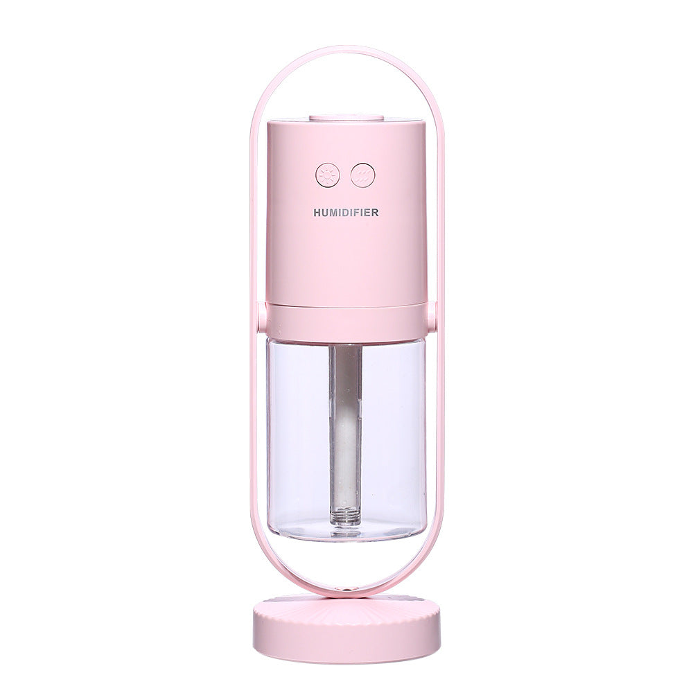 A cylindrical pink USB air humidifier with a transparent water tank is cradled in a metallic arc stand.