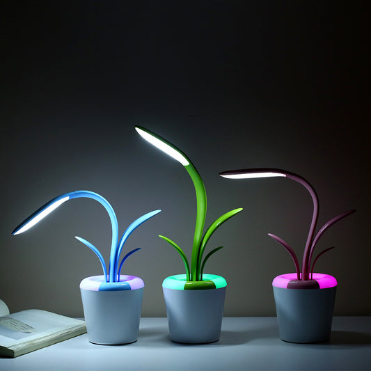 This image shows three  LED Table Lamps with a stylized, plant-like design in blue, green, and pink colors. They have flexible stems and illuminated leaves, creating a soothing and modern atmosphere. The lamps are displayed on a table against a dark background, highlighting their vibrant glow and sleek, pot-like bases.