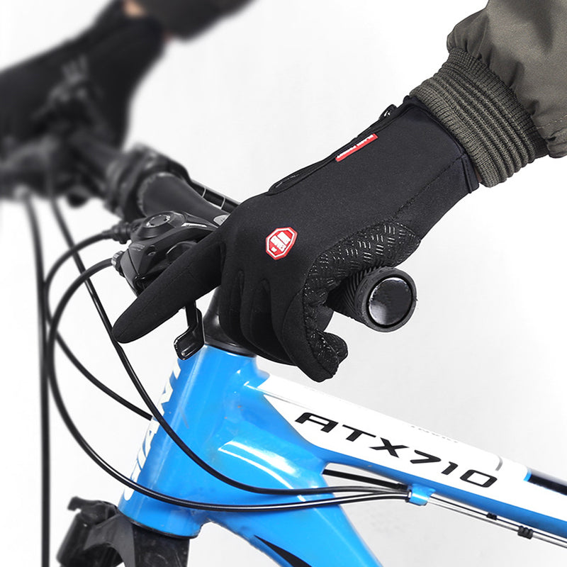 A cyclist wearing the gloves is riding a bike in a wintry setting, emphasizing the gloves' suitability for outdoor sports in cold conditions.