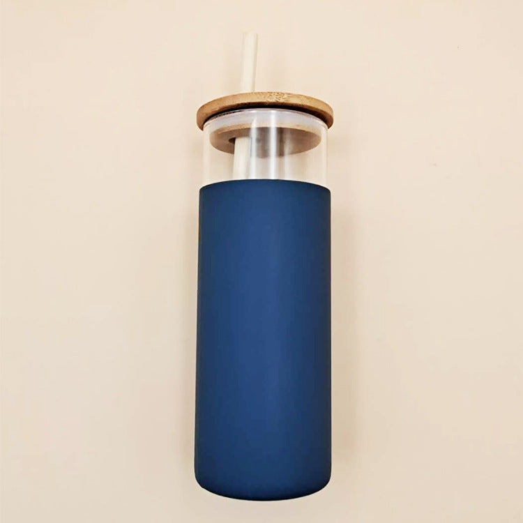 Side view of a navy glass cup with its lid and straw leaning against a white cup, showcasing the contrast in colors and the assembly of the lid on the cu
