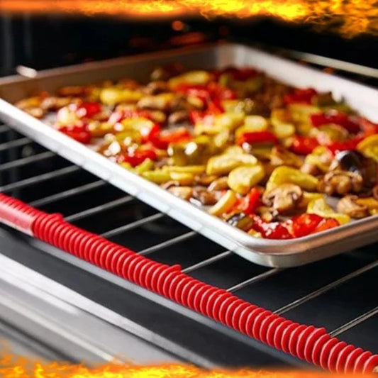 The image shows a brightly colored silicone anti-scalding strip applied to the edge of an oven rack. The strip appears as a vibrant red, spiral-shaped cord against the metal rack. Below the rack, there are vegetables being roasted in a tray, indicating the strip's heat-resistant function in a working oven.