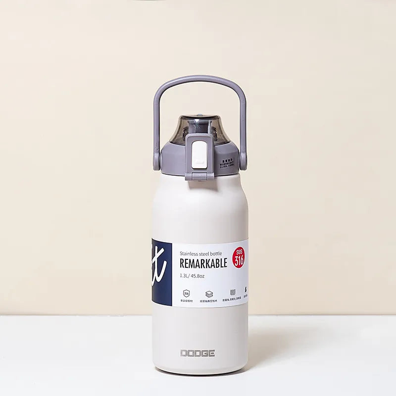 The image displays a matte white stainless steel thermal water bottle with a sturdy handle on the lid. The bottle is labeled "REMARKABLE 316", indicating the grade of stainless steel, and has a capacity of 1.3L/45.8oz as stated on its label