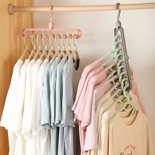 A collection of pastel-colored shirts hangs neatly on a pale pink multi-port clothes hanger against a wooden rod, demonstrating the hanger's space-saving design.