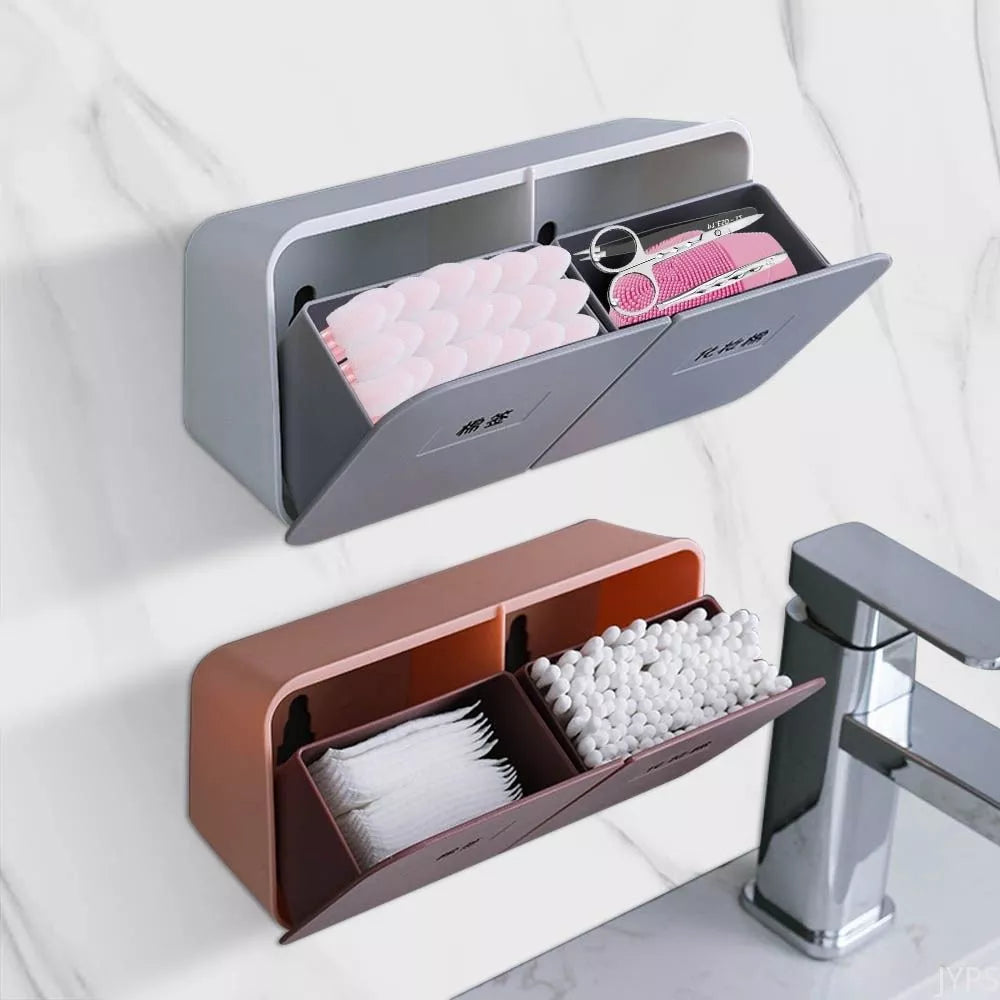 The image shows a compact, wall-mounted bathroom organizer with multiple compartments. The top section with a flip cover houses cotton pads and personal care items, while the bottom open compartment contains cotton swabs.