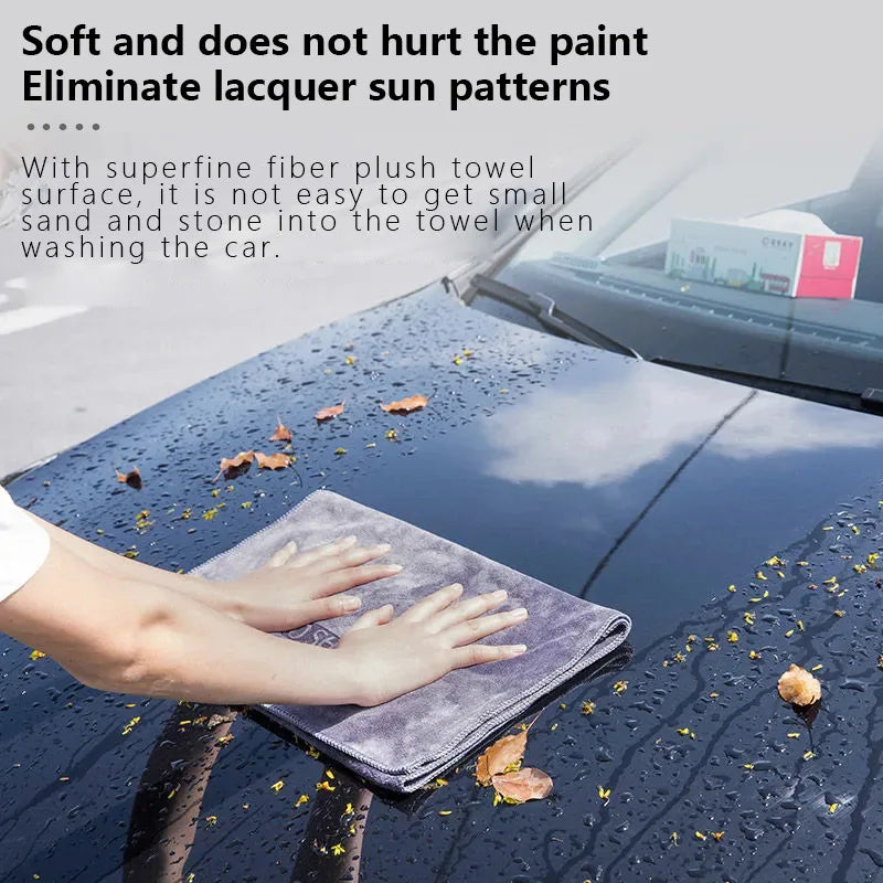 Grey microfiber towel in hand, wiping off droplets from a car’s dark reflective surface, leaving a clean streak.