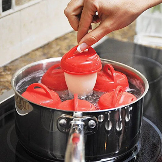 The image depicts a hand lifting a red silicone egg cooker from a pot of boiling water, surrounded by other cookers. The cookers have a bulbous base and a flatter, circular lid, highlighting their use in making boiled or poached eggs.