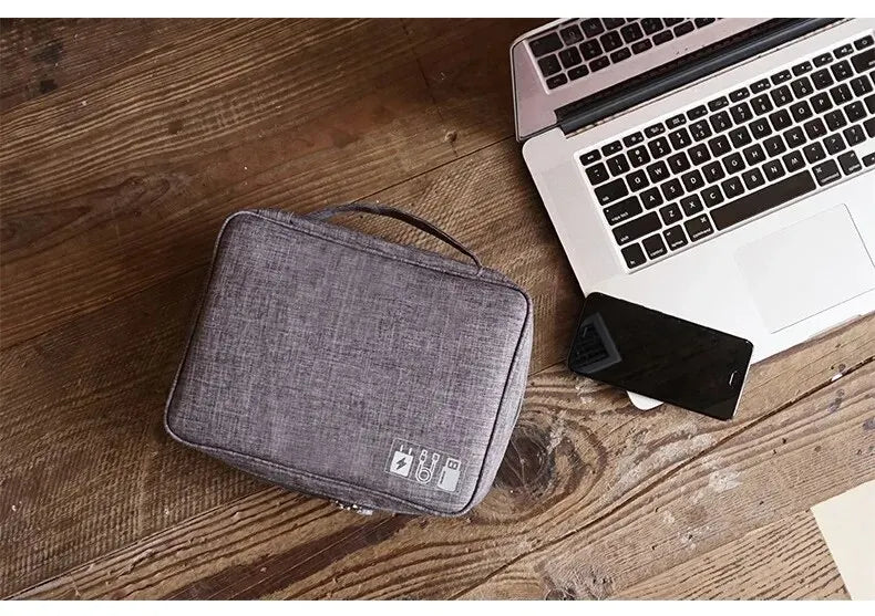 The grey cable management bag closed, showing its compact and portable design, perfect for carrying in a backpack or suitcase during travel.