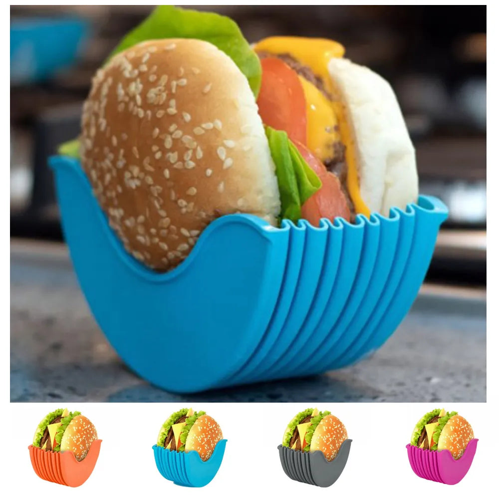 The image displays a vibrant blue silicone burger holder cradling a fully assembled hamburger with visible layers of lettuce, tomato, cheese, and a beef patty. Below are smaller images showing the holder in grey, orange, and pink colors, illustrating the product's variety and functionality.