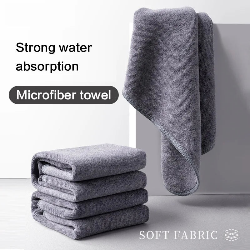 Pile of three folded grey microfiber towels, showcasing their thickness and plush surface.