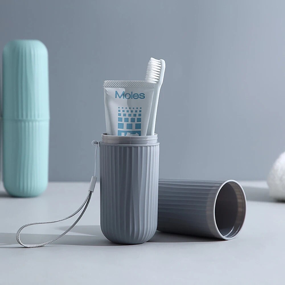 An image showing a grey toothbrush cup with its cap off, next to an open cup holding a toothbrush, on a dark grey surface.