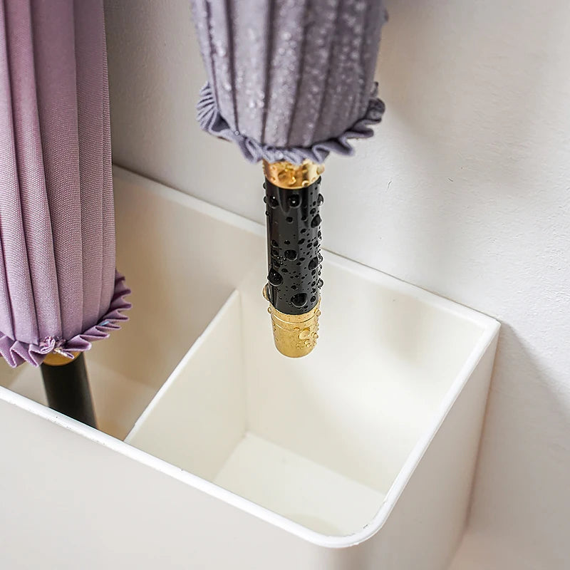 Close-up of the umbrella tips resting inside the multi-functional storage rack, highlighting the water-resistant feature that keeps floors dry.