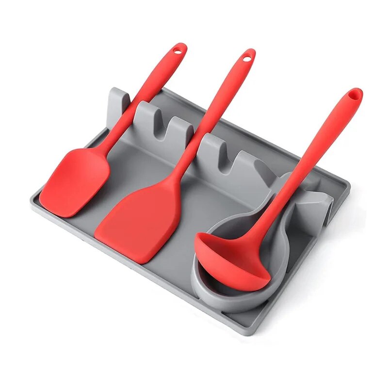 The photo illustrates a silicone utensil holder in use on a countertop, holding a spatula and two spoons with red handles, demonstrating the product's functionality.