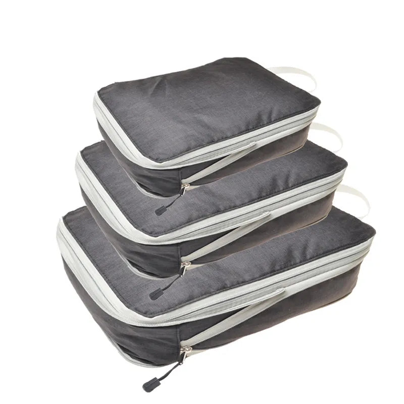 A stack of gray packing cubes in various sizes, demonstrating the space-saving benefit when clothes are compressed.