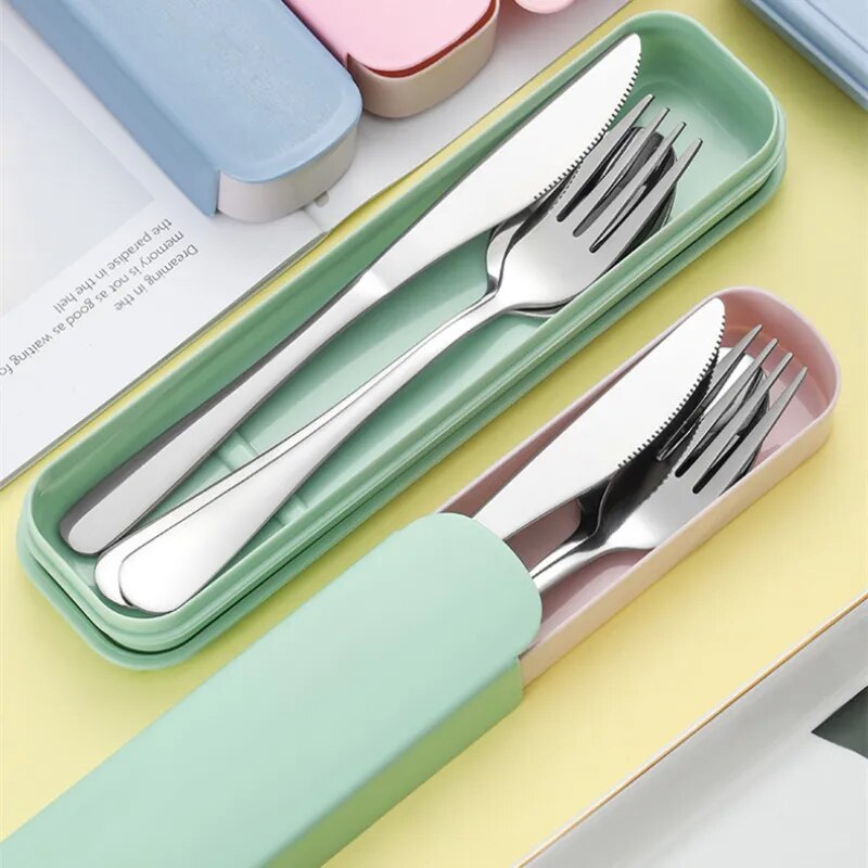 Two sets of stainless steel cutlery; one nestled in a mint green box with the lid off, the other partially inserted into a pastel pink silicone sleeve, both against a pastel background.