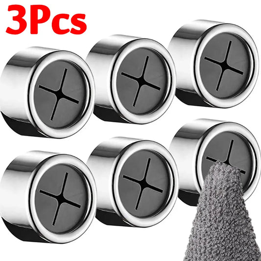The image displays a set of three cylindrical, punch-free towel plug holders with a shiny chrome finish. Each holder has a black cross-shaped slot in the center, designed to grip and hold the corner of a towel. One holder is in use, gripping a grey towel, illustrating the product's function. The text "3PCs" is prominently displayed, indicating the quantity in the set.