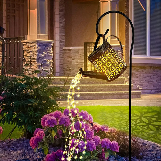 The Enchanting Solar Watering Can Light illuminates a garden pathway at night, creating a cascading water effect with LED lights. Ideal for outdoor solar lights.