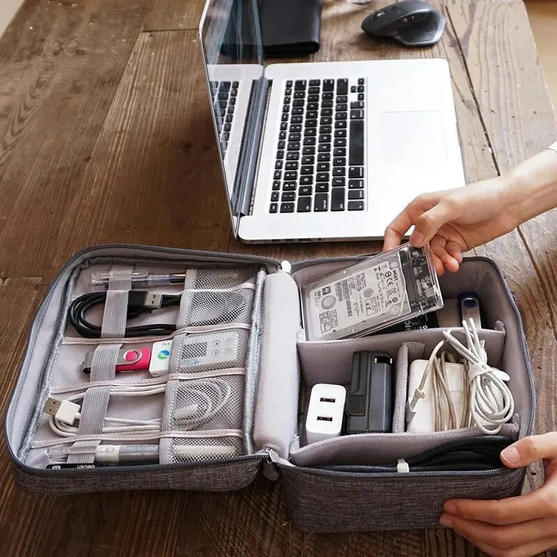 The cable storage bag placed next to a laptop, demonstrating its compact size and how it fits easily into a workspace for efficient cable management.