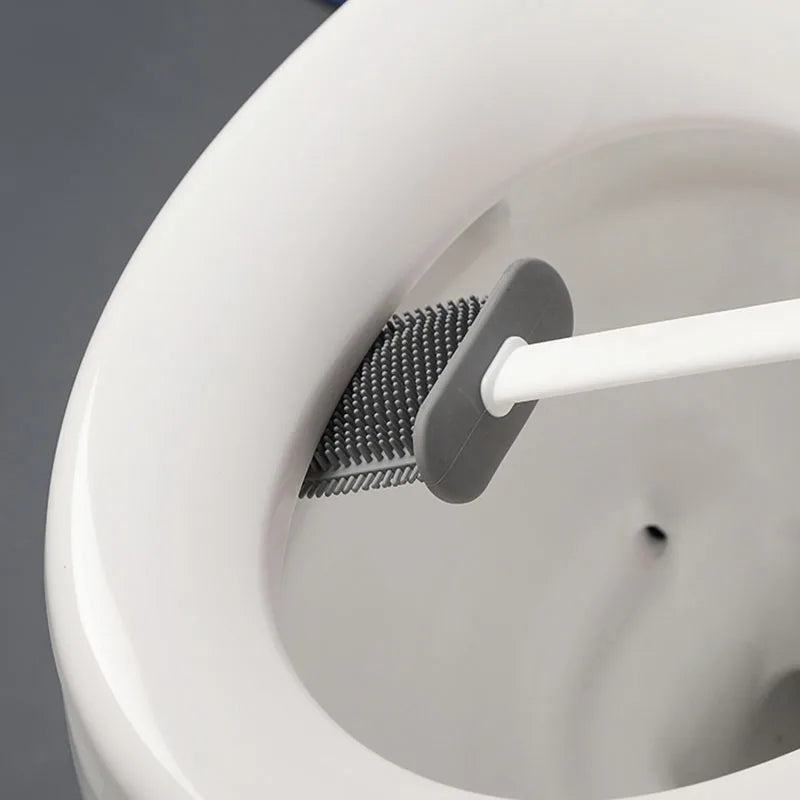 toilet brush in use, with a close-up on the bristles as they scrub the inside rim of a toilet bowl.