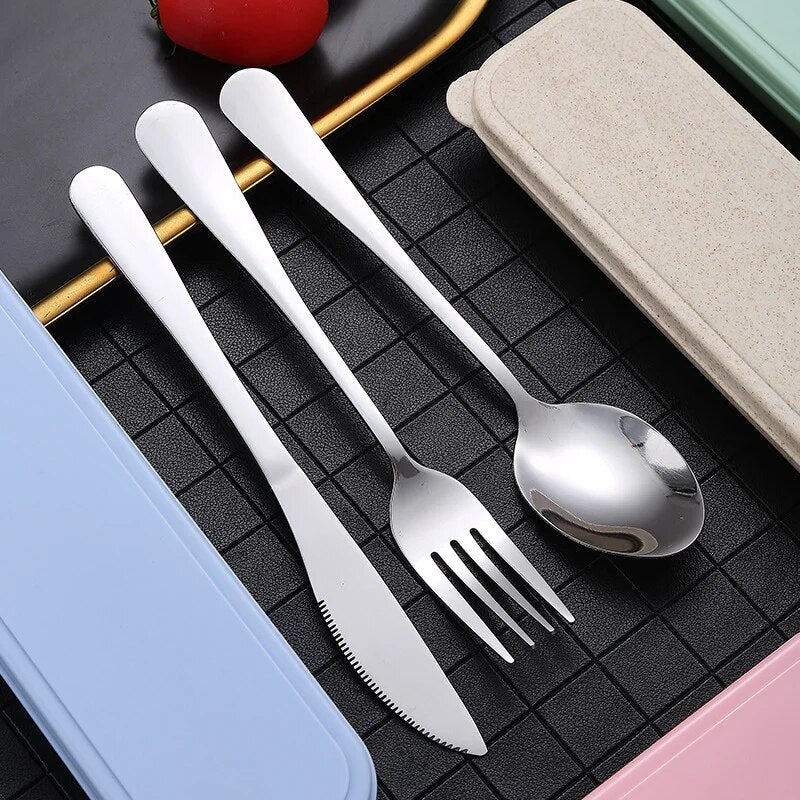 An individual display of a stainless steel spoon, knife, and fork lying side by side on a dark surface, highlighting their silver sheen and ergonomic design.