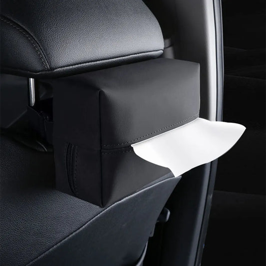 The image features a sophisticated black leather car tissue box holder strapped to the back of a car's headrest. The box displays a flap that opens to reveal white tissues, indicating easy access for passengers. The holder's sleek design and contrasting white stitching compliment the car's interior, providing both functionality and a touch of elegance.