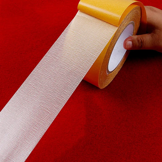 A roll of translucent double-sided tape with a mesh-like texture against a red background