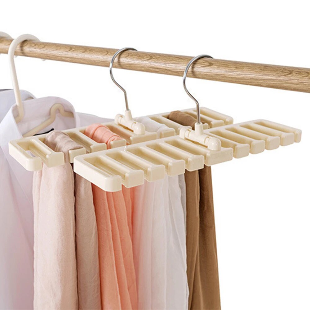 image shows a cream-colored tie and belt hanger with numerous slots, holding pastel-colored scarves and hanging from a wooden rod.