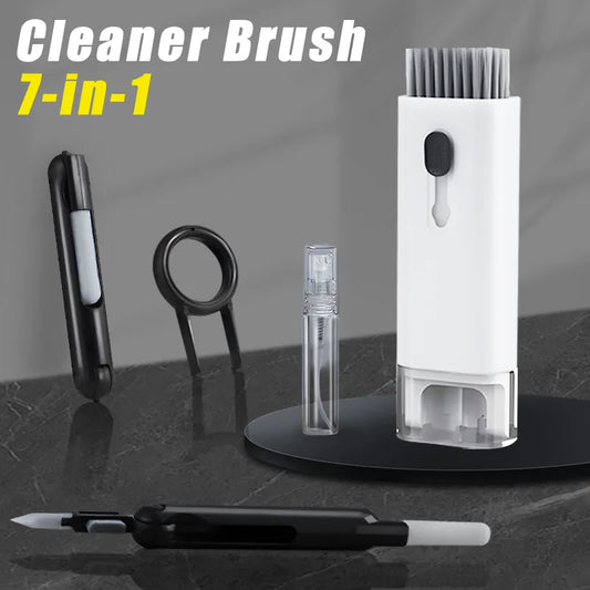 Image of a 7-in-1 cleaner brush kit displayed on a dark surface; includes a standing cylindrical case with slots holding a spray bottle, two brushes, a cleaning pen, and a keycap puller