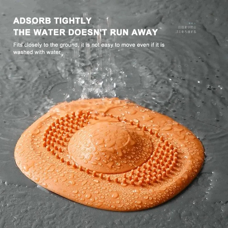 An orange sink strainer is shown on a surface with water droplets around it, highlighting its texture designed to prevent clogging.