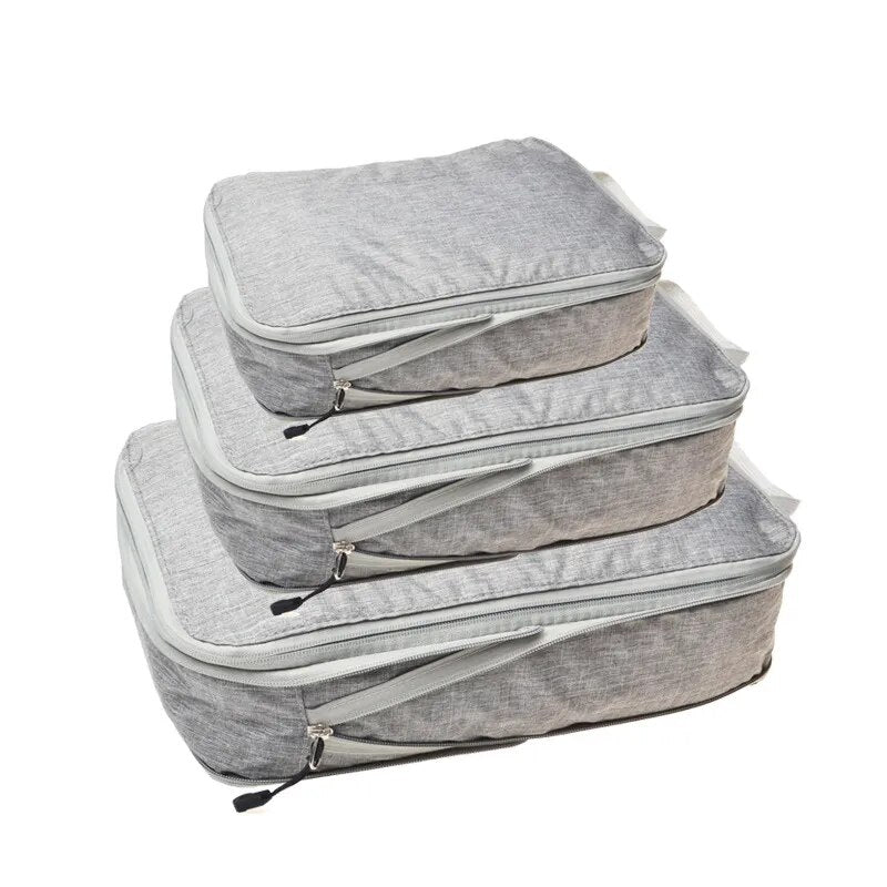 A stack of gray packing cubes in various sizes, demonstrating the space-saving benefit when clothes are compressed.