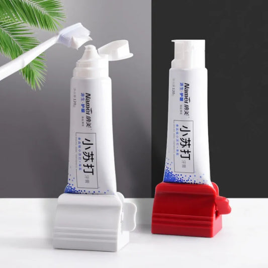 Two toothpaste squeezers, one red and one white, with a toothpaste tube inserted, stand against a white backdrop