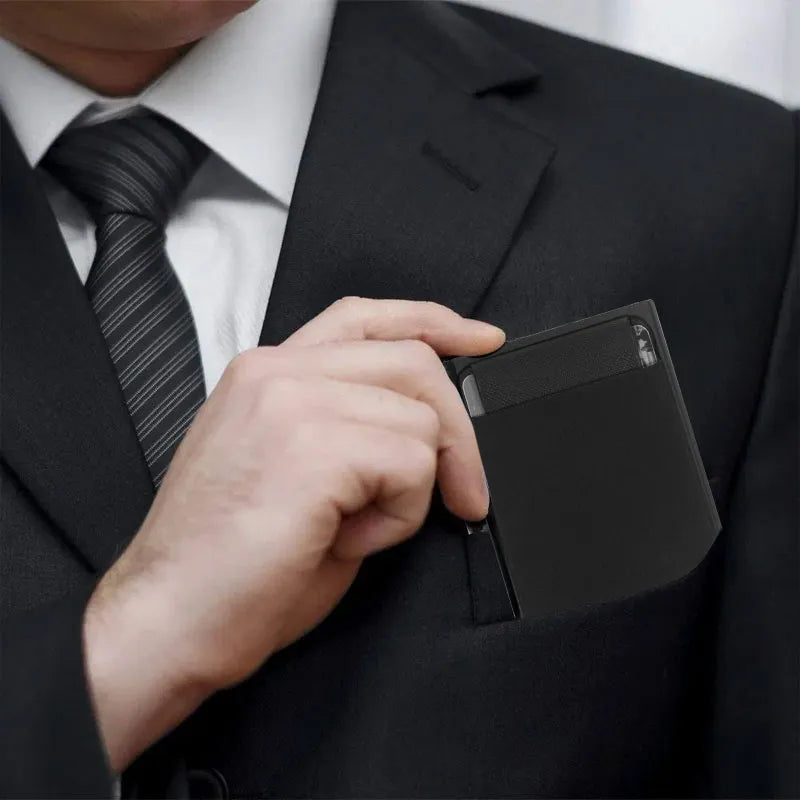 The wallet in a hand, subtly being slid into a suit jacket pocket, emphasizing its sleek design suitable for formal attire.