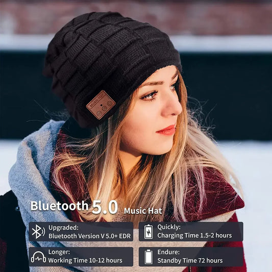 A woman in a winter setting wearing a black knitted beanie with a visible Bluetooth control panel on the side.