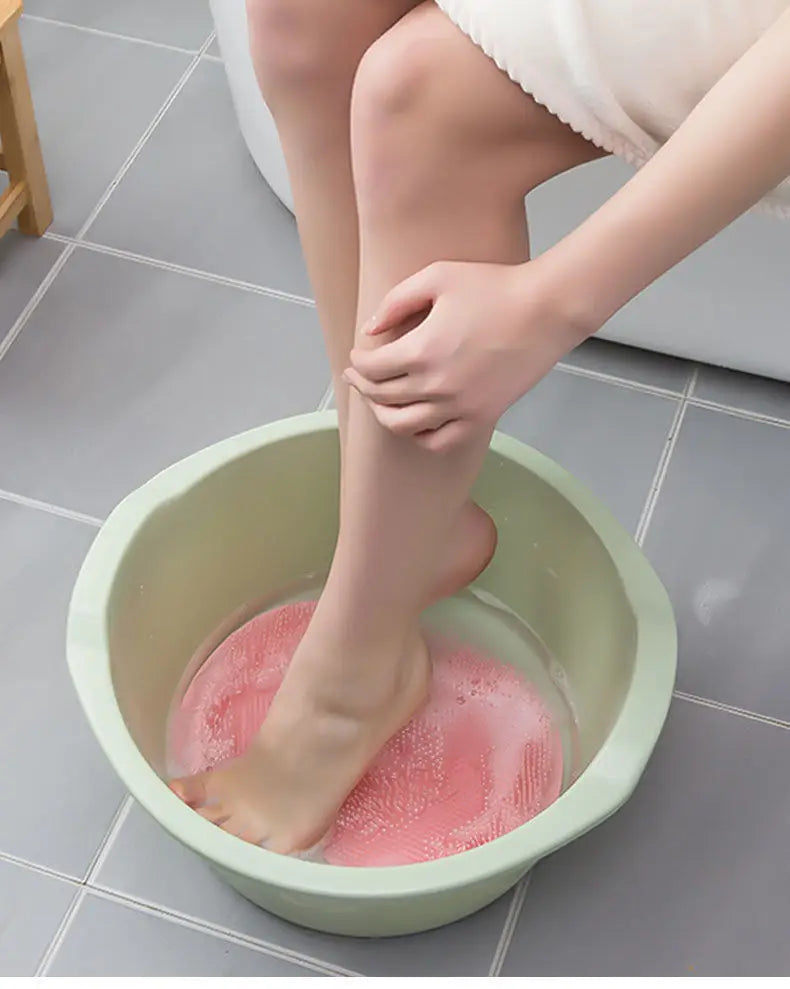 foot pressing down on a pink silicone scrubber 