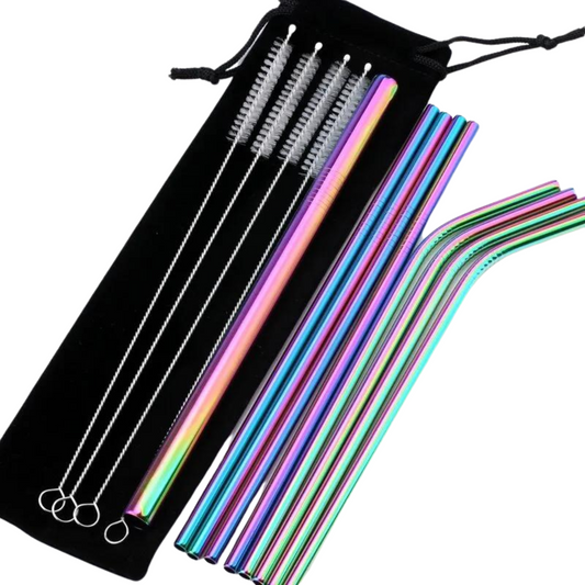 The image displays a collection of metal reusable straws in a variety of colors including silver, rainbow, purple, blue, and rose gold, along with matching cleaning brushes. They are laid out on a flat surface next to a black drawstring bag, showcasing both straight and bent straws that reflect light with a metallic sheen.